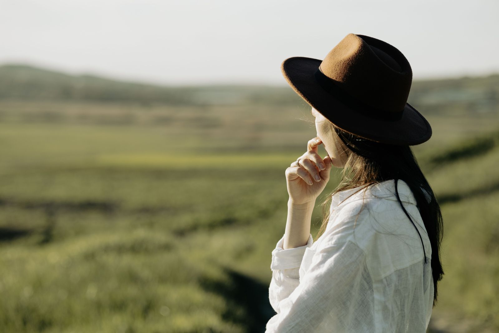 A woman in a hat looking out over open fields