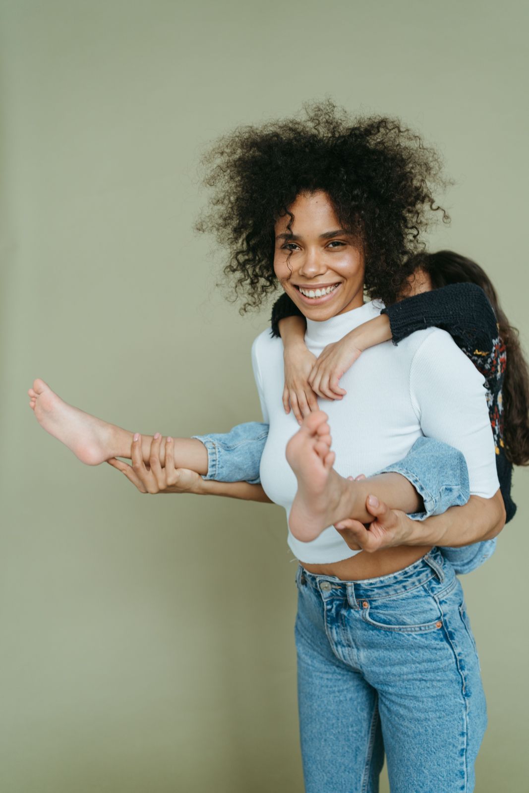 A smiling mum carrying her daughter on her back